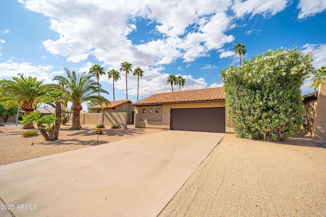 view of front of house with concrete driveway, a tiled roof, stucco siding, an attached garage, and fence