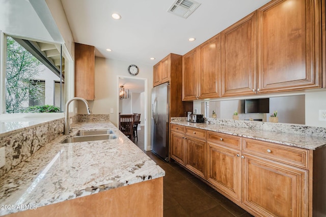 kitchen featuring recessed lighting, light stone countertops, a sink, stainless steel fridge, and visible vents