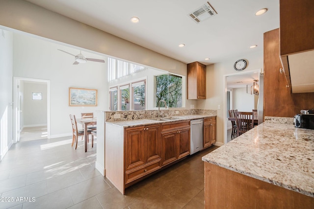 kitchen featuring light stone counters, visible vents, dishwasher, and brown cabinetry