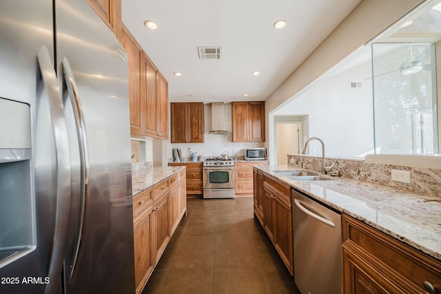 kitchen with a sink, visible vents, stainless steel appliances, wall chimney exhaust hood, and dark tile patterned flooring