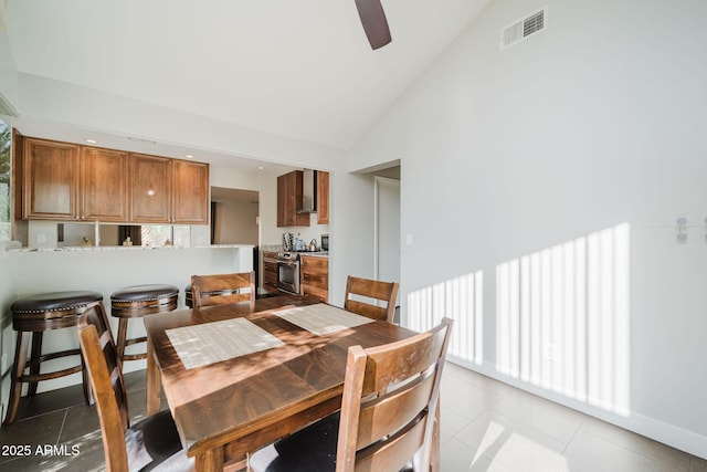 dining space featuring light tile patterned floors, visible vents, ceiling fan, and high vaulted ceiling