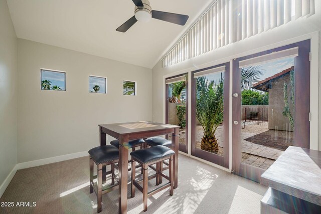 carpeted dining area with ceiling fan, high vaulted ceiling, and baseboards
