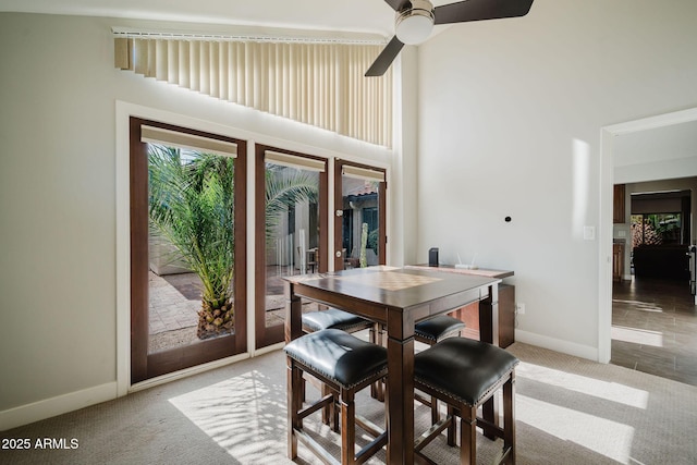 dining area featuring carpet, baseboards, a ceiling fan, a high ceiling, and french doors