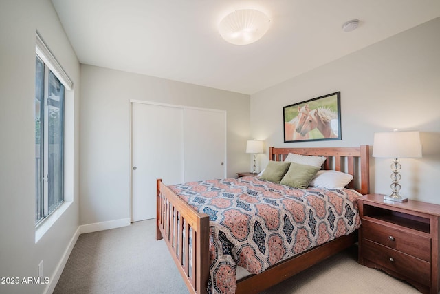 bedroom with light colored carpet, baseboards, and a closet