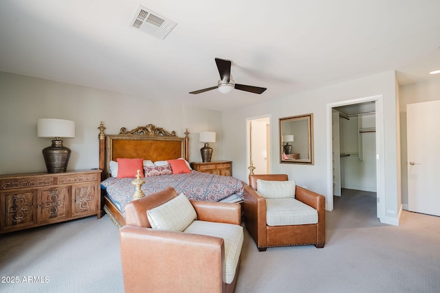 bedroom featuring a closet, light carpet, ceiling fan, a walk in closet, and visible vents