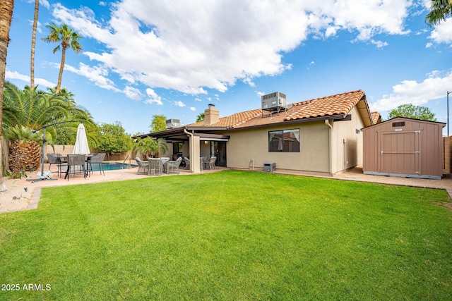 back of house featuring a storage unit, a patio area, an outbuilding, a yard, and a fenced backyard