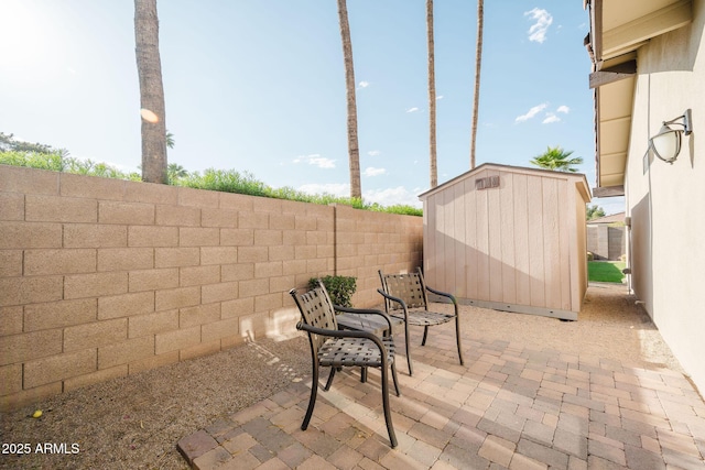 view of patio / terrace with a storage unit, a fenced backyard, and an outdoor structure