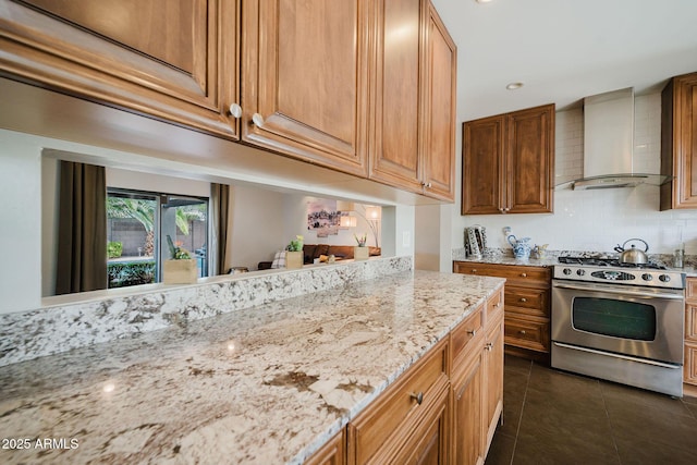 kitchen featuring light stone countertops, dark tile patterned flooring, gas range, backsplash, and wall chimney exhaust hood