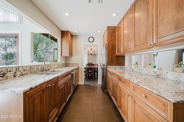 kitchen featuring light stone counters, a sink, appliances with stainless steel finishes, recessed lighting, and dark tile patterned flooring