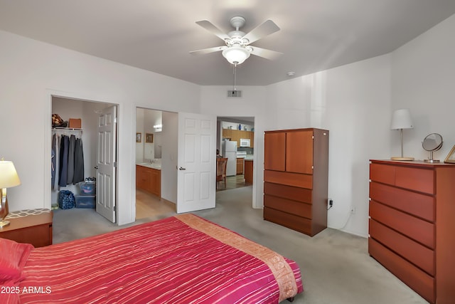 bedroom with ceiling fan, a spacious closet, light carpet, a closet, and white refrigerator