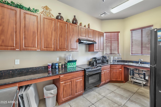 kitchen with sink, light tile patterned floors, black appliances, and dark stone counters