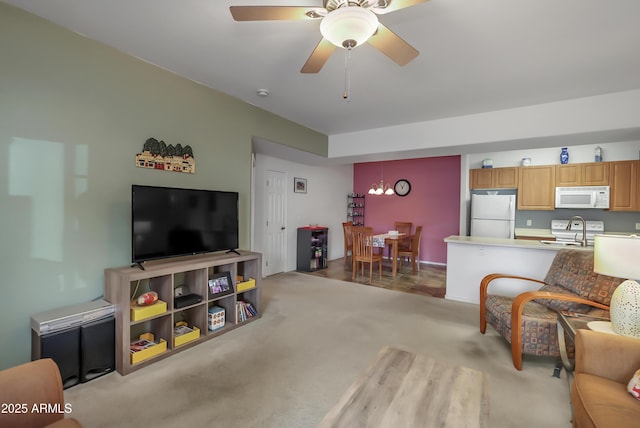 living room featuring light carpet, ceiling fan with notable chandelier, and sink