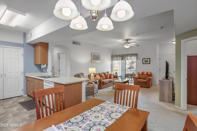 dining space featuring light colored carpet, ceiling fan with notable chandelier, and sink