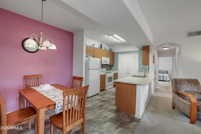 kitchen featuring decorative light fixtures, kitchen peninsula, sink, white appliances, and a chandelier