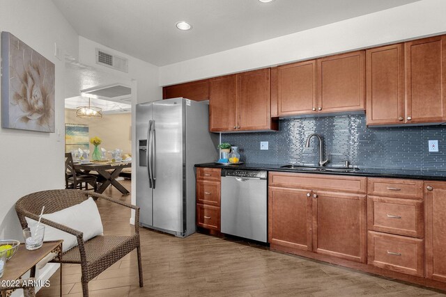 kitchen featuring appliances with stainless steel finishes, sink, light hardwood / wood-style flooring, and tasteful backsplash