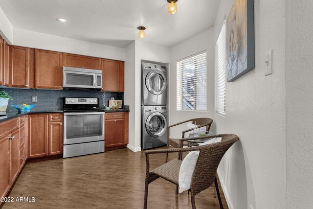 kitchen with stacked washer and dryer, dark hardwood / wood-style flooring, tasteful backsplash, and appliances with stainless steel finishes