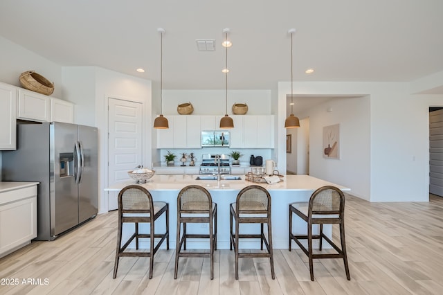 kitchen with visible vents, white cabinets, stainless steel appliances, and a kitchen bar