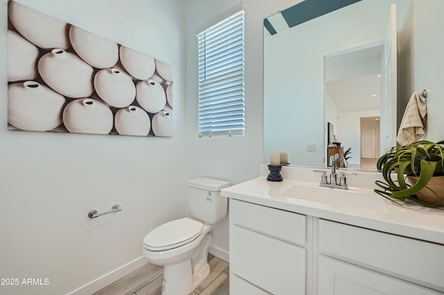 bathroom with vanity, toilet, wood finished floors, and baseboards