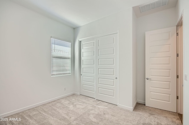 unfurnished bedroom featuring baseboards, visible vents, light carpet, and a closet
