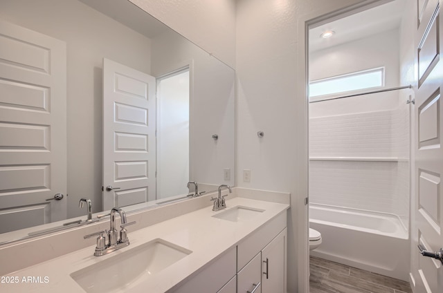 full bathroom featuring double vanity, toilet, wood finished floors, and a sink