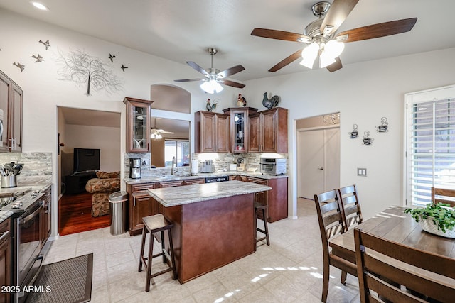 kitchen featuring a kitchen breakfast bar, decorative backsplash, a center island, and stainless steel range oven