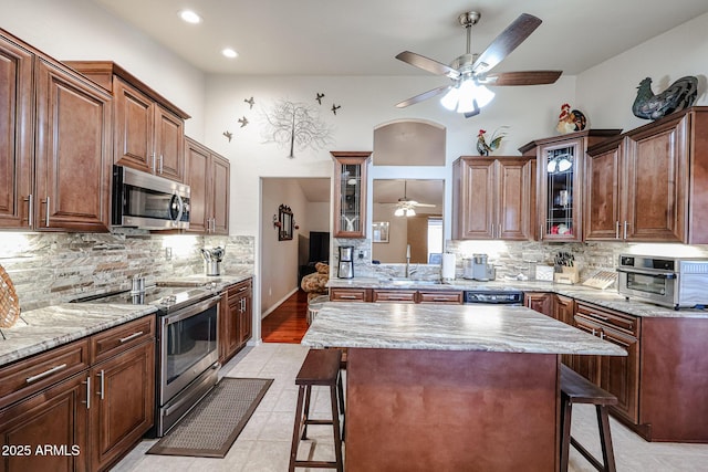 kitchen with a kitchen island, a kitchen bar, light tile patterned floors, and stainless steel appliances