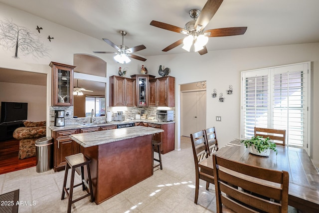 kitchen with a center island, sink, tasteful backsplash, lofted ceiling, and a breakfast bar