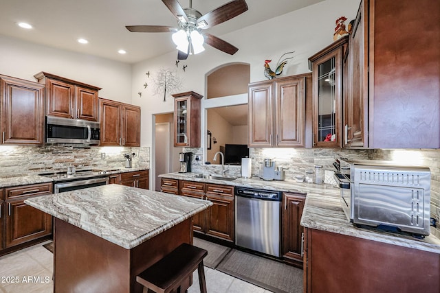 kitchen featuring a center island, backsplash, sink, light tile patterned floors, and stainless steel appliances