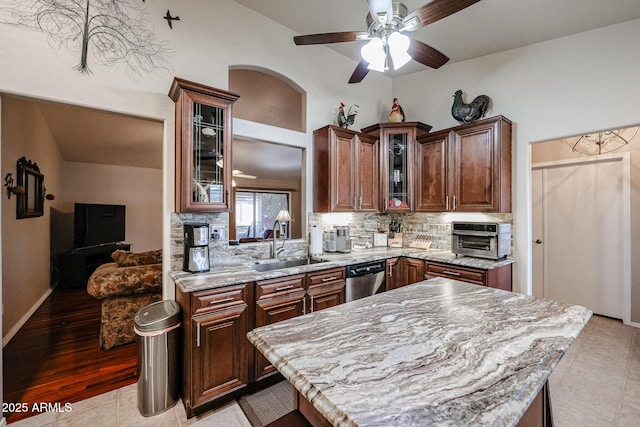 kitchen featuring backsplash, light stone counters, sink, light tile patterned floors, and dishwasher