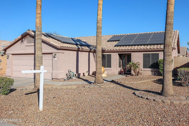 rear view of house featuring solar panels and a garage