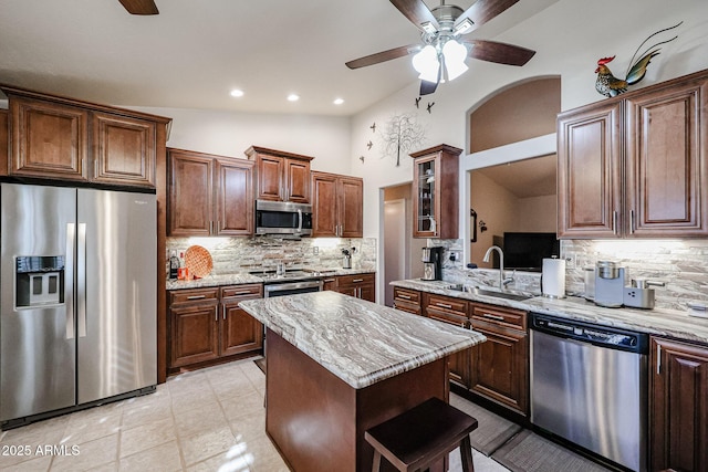 kitchen featuring a center island, light stone counters, backsplash, lofted ceiling, and appliances with stainless steel finishes