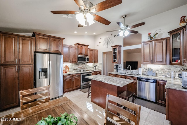 kitchen with backsplash, vaulted ceiling, light tile patterned flooring, light stone counters, and stainless steel appliances