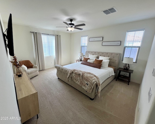 bedroom featuring ceiling fan, light colored carpet, and multiple windows