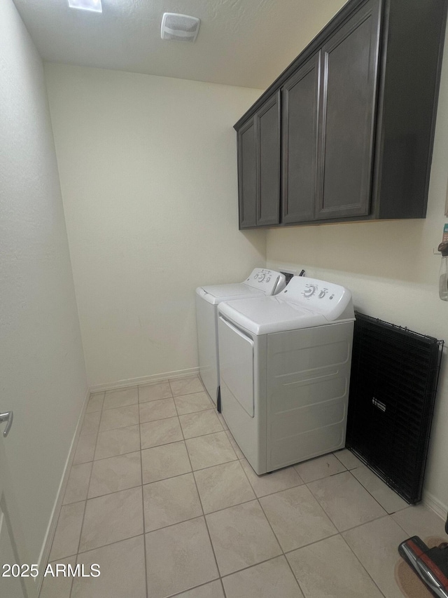 washroom with light tile patterned flooring, cabinets, and washing machine and dryer