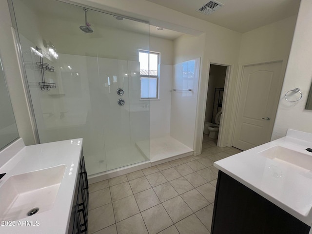 bathroom featuring tile patterned floors, vanity, toilet, and a tile shower