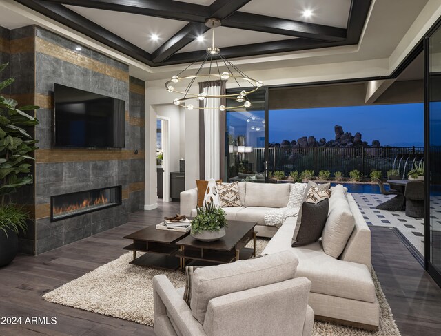 living room with a tile fireplace, coffered ceiling, an inviting chandelier, beamed ceiling, and wood-type flooring