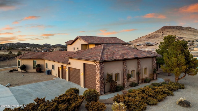 view of front facade with cooling unit, a mountain view, and a garage