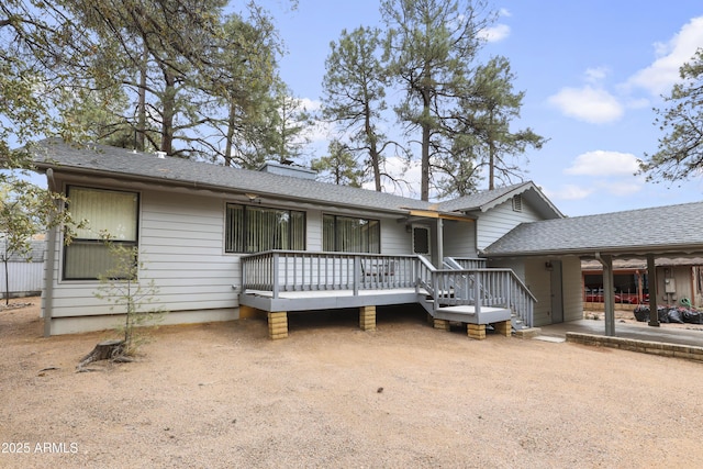 view of front of property with dirt driveway, a deck, and roof with shingles