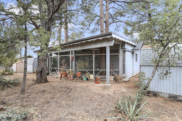 rear view of house with a storage unit, an outdoor structure, and a sunroom