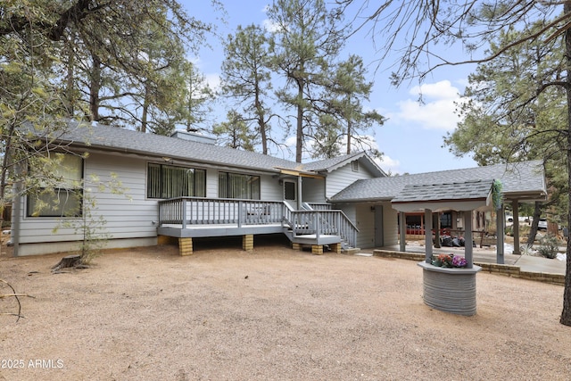 back of house featuring a patio, a shingled roof, driveway, a wooden deck, and a chimney