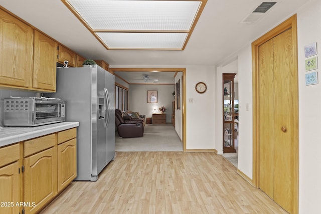 kitchen with a toaster, tile countertops, visible vents, light wood-style floors, and open floor plan