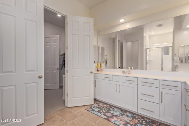 bathroom featuring tile patterned flooring, vanity, vaulted ceiling, and walk in shower