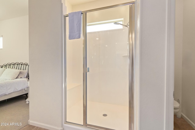 bathroom with tile patterned flooring, toilet, and an enclosed shower