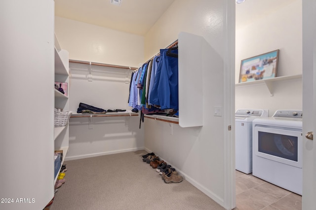 walk in closet featuring washing machine and clothes dryer and light carpet