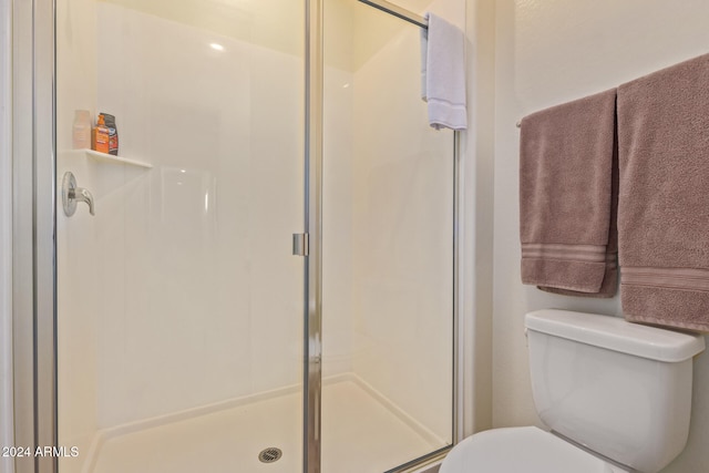 bathroom with a shower with shower door and toilet