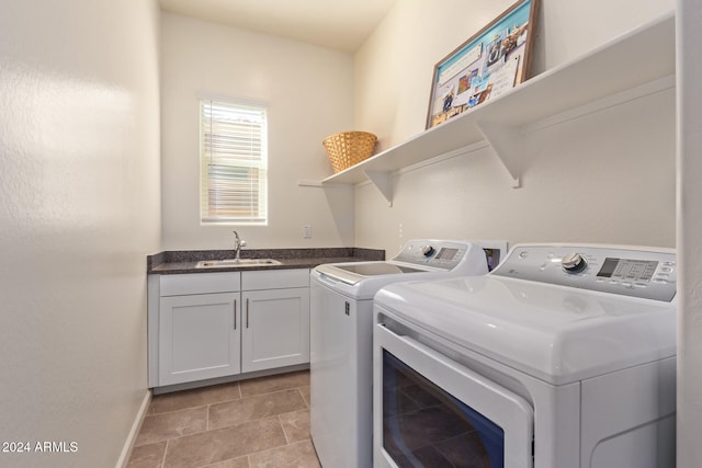 washroom with cabinets, washing machine and dryer, and sink