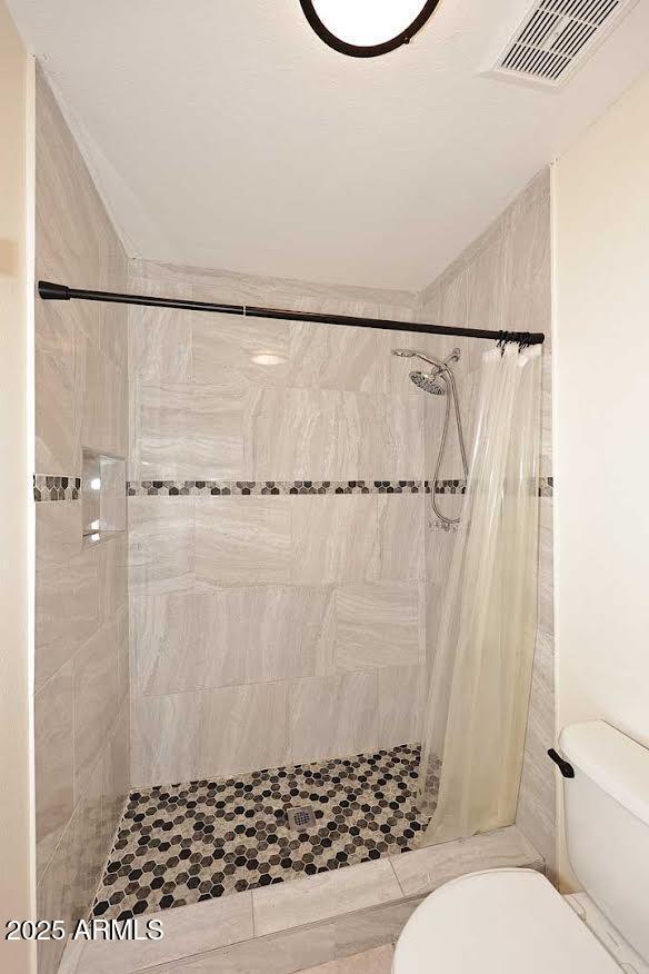 bathroom with toilet and a shower with shower curtain