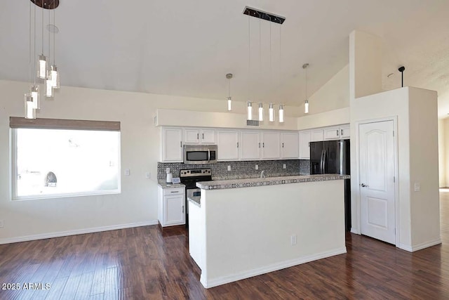 kitchen with high vaulted ceiling, appliances with stainless steel finishes, tasteful backsplash, and white cabinetry