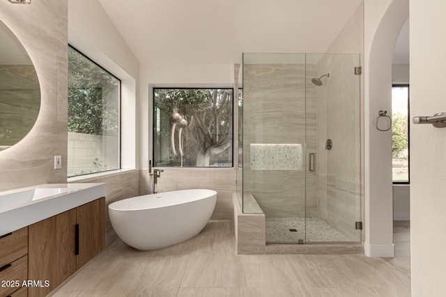 bathroom featuring separate shower and tub, vanity, vaulted ceiling, and a healthy amount of sunlight