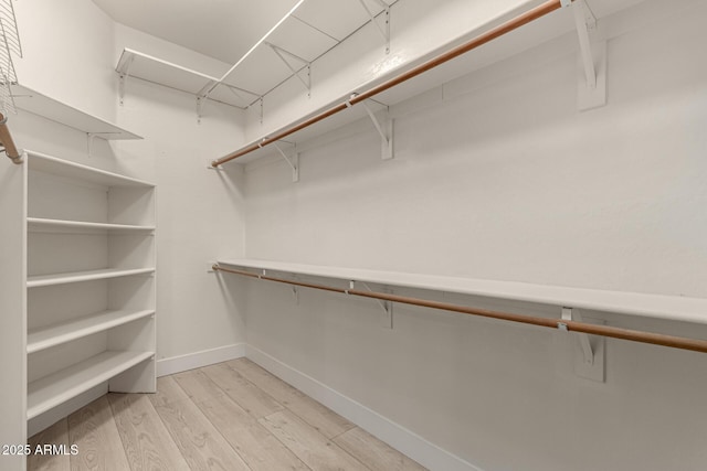 walk in closet with light hardwood / wood-style floors